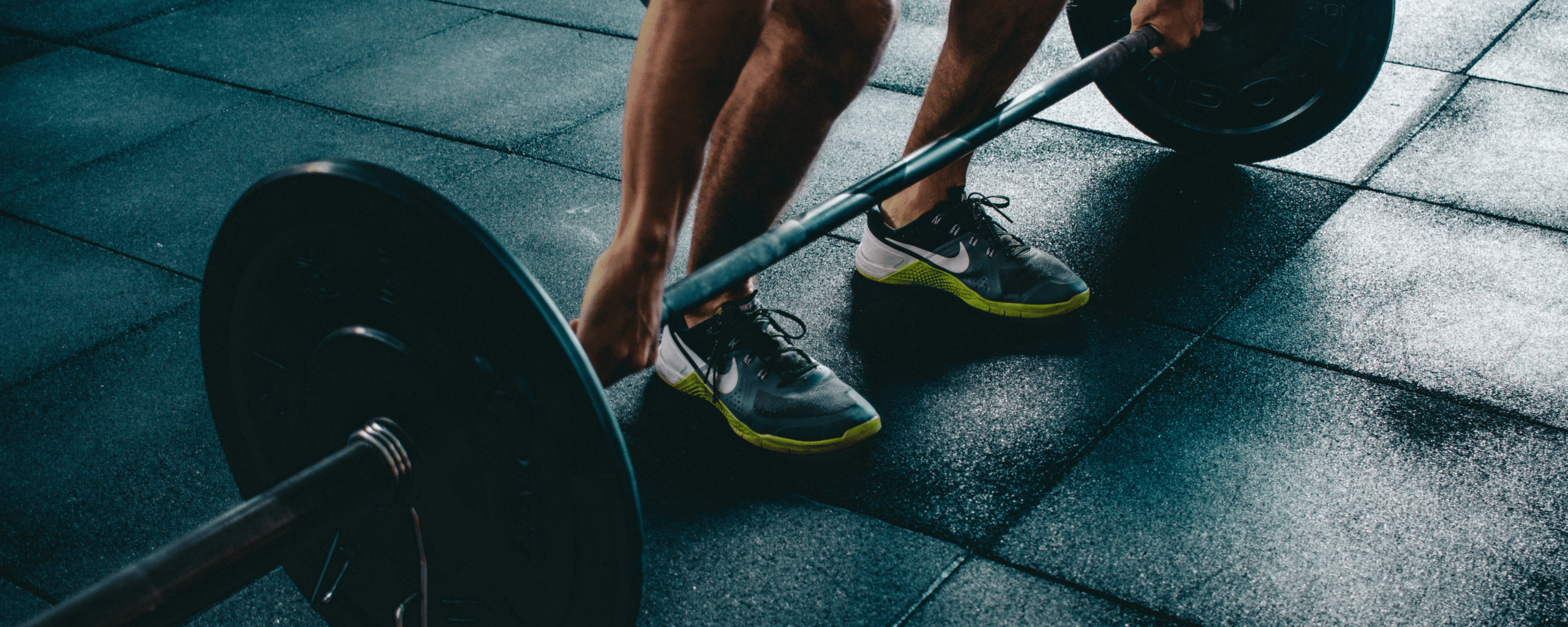 Man weight lifting a barbell with weights in a gym, dark colors